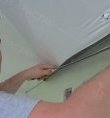 Специалист устраняет дефекты на натяжном потолке